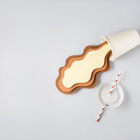 Creative concept photo of take away cup with splashing coffee made of paper on grey background.の写真素材
