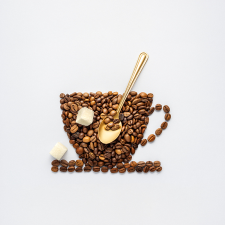 Creative concept photo of coffee cup made of beans with spoon and sugar on grey background.