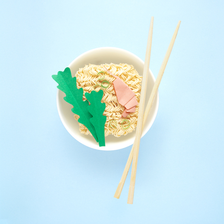 Creative food diet healthy eating concept photo of tasty ramen noodle pasta with shrimps prawns greens chopsticks and bowl on blue background.の写真素材