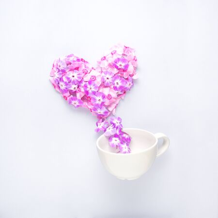 Creative concept still life valentine day photo of flowers in bloom in shape of heart with coffee drink beverage cup mug on grey background.の写真素材
