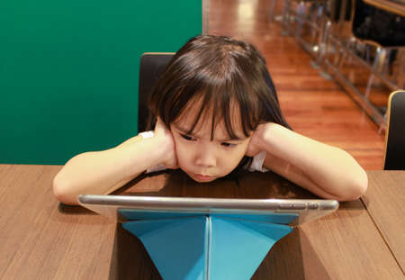 Little girl looking at tablet on public. education, school, technology and internet concept.