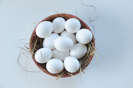 white chicken eggs in a ceramic bowl on a light background. High quality photo