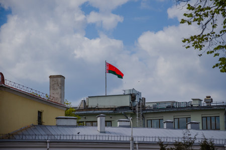 red-green Belarusian flag on the roof of a house against the blue sky, Republic of Belarus. High quality photoの写真素材