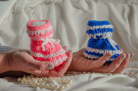 Hold children's knitted socks in pink and blue in your hands, the concept of giving birth to a boy...