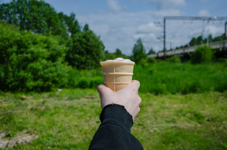 Ice cream in a waffle cup in your hand against nature background. High quality photoの写真素材