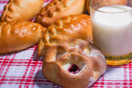 Hot tasty pies on red tablecloth with cup of milkの写真素材