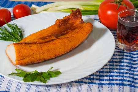 Appetizing piece of smoked bacon on a white plate, served with tomatoes, greens and glass apperetivaの写真素材