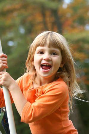 Little girl playing on swing with big smile.の写真素材