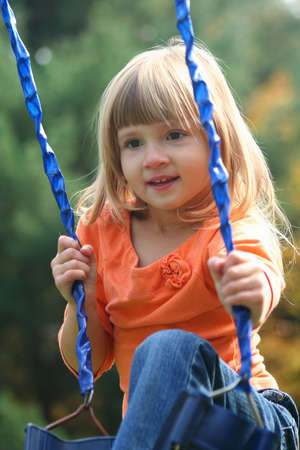 Little girl sitting on swing outdoors.の写真素材