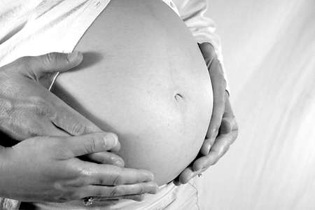 Womans belly with man and womans hands.の写真素材