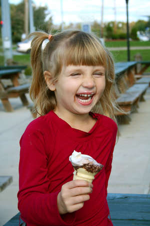 Little girl laughing eating icecream cone.の写真素材