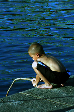 Young boy fishing by river.の写真素材