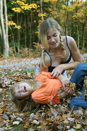 Big sister tickling little sister outdoors.の写真素材