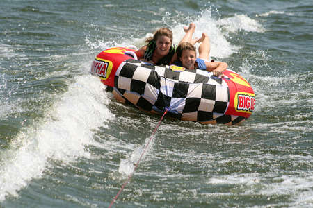 Teenage girls tubing on lake.の写真素材