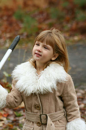 Little girl ready to rake autumn leaves.の写真素材