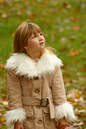 Little girl wearing warm coat in autumn.の写真素材