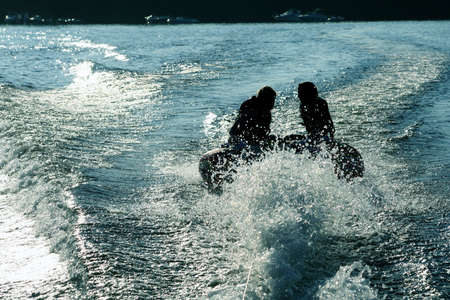 Silhoette of two girls tubing on lake.の写真素材