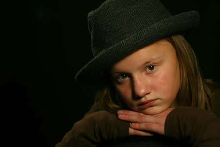 Young girl wearing fedora hat isolated on black