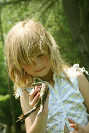 Little girl outdoors holding a toadの写真素材