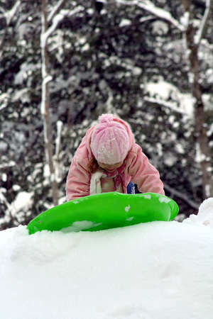 Little girl sledding on hill in winterの写真素材