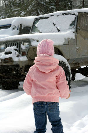 Little girl outdoors in snow near off road vehicleの写真素材