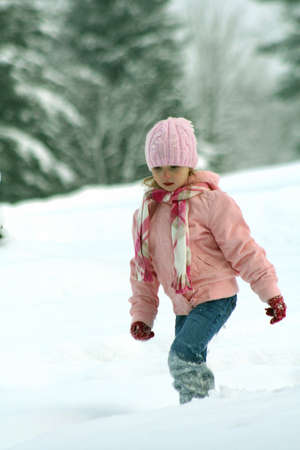 Little girl dressed in pink walking through snowの写真素材