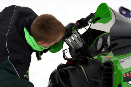 Teenager checking out snowmobileの写真素材