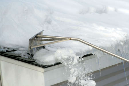 snow rake removing snow and ice from roofの写真素材