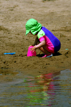 Little girl playing in sand at beachの写真素材