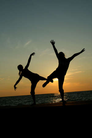 Silhoette of two teenagers dancing at sunsetの写真素材