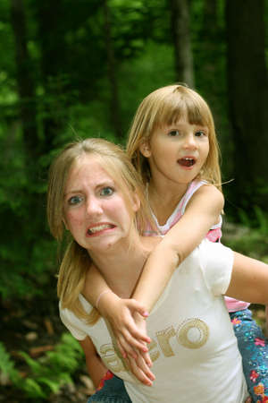 Big sister giving little sister piggy back rideの写真素材