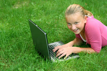Smiling young girl outdoors on computerの写真素材
