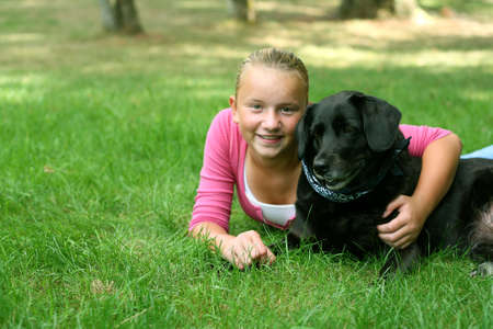 Preteen girl outdoors with black labrador dogの写真素材