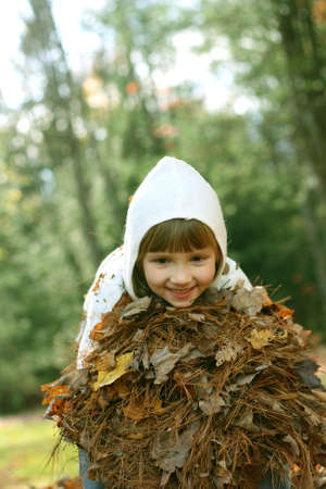 Little girl playing in the leaves on autumn dayの写真素材