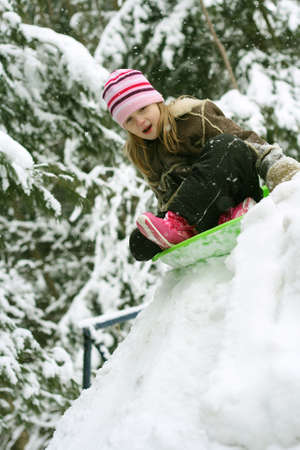 Little girl on green sled in snowの写真素材