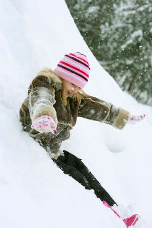 Little girl sledding down hillの写真素材