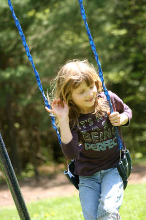 Little Girl Swinging on Swing on Spring Dayの写真素材