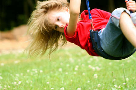 Little girl swinging high on swingsetの写真素材