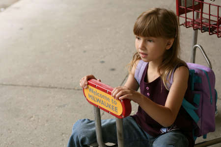 Little girl on baggage cart outside airportの写真素材