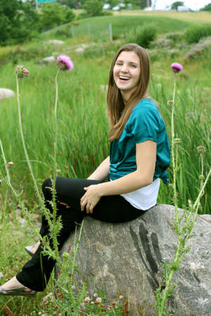 Teenager sitting on rock surrounded by flowersの写真素材