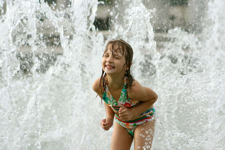 Little girl cooling off in city fountainの写真素材