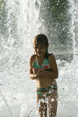 Little girl playing in fountainの写真素材