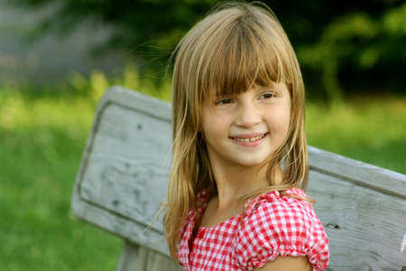 smiling little girl sitting on park benchの写真素材
