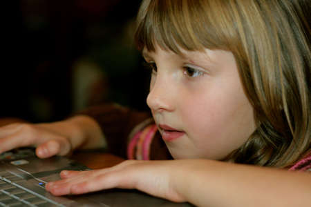 little girl on laptop playing gamesの写真素材
