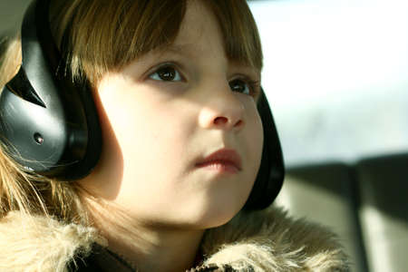 Little girl in car wearing headphones and watching dvdの写真素材