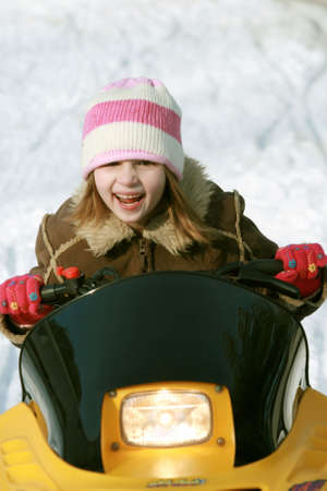 Little girl having fun driving a snowmobileの写真素材
