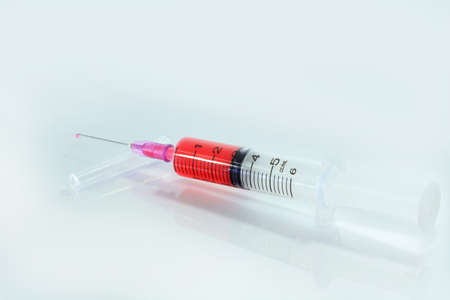 syringe filled with red liquid. Isolated on white.の写真素材