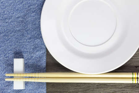 wood background plates, chopsticks and spoons on blue jeans textureの写真素材