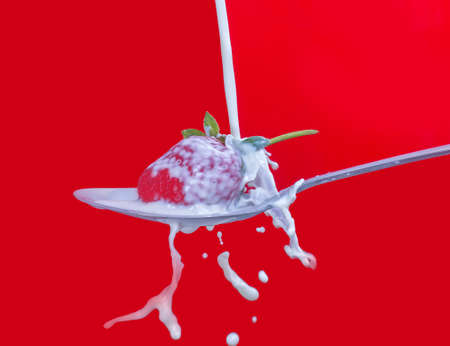 fresh strawberry splashing into spoon full of milkの写真素材