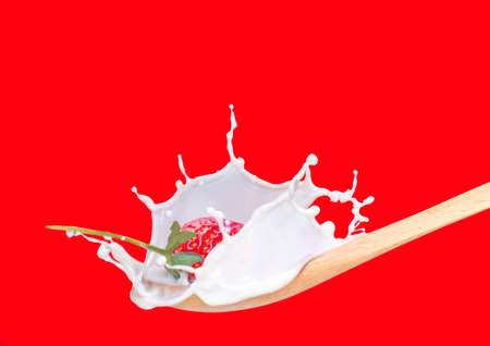 fresh strawberry splashing into spoon full of milkの写真素材
